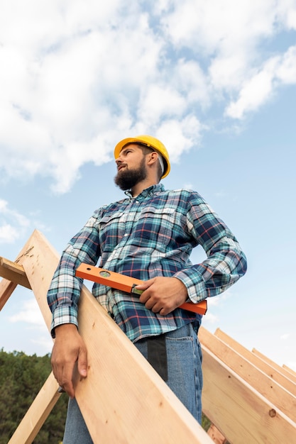 Trabajador con nivel de construcción del techo de la casa.