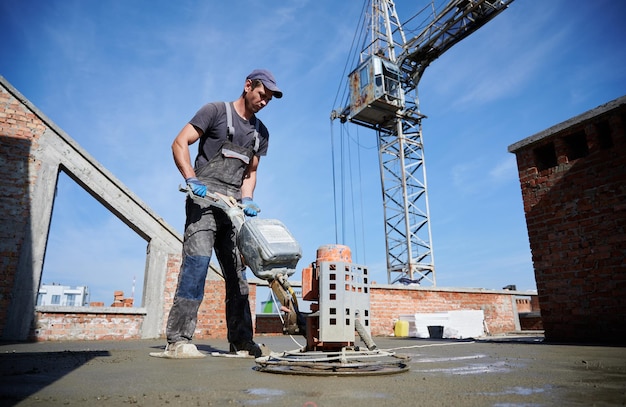 Trabajador nivelando piso fresco con máquina especial