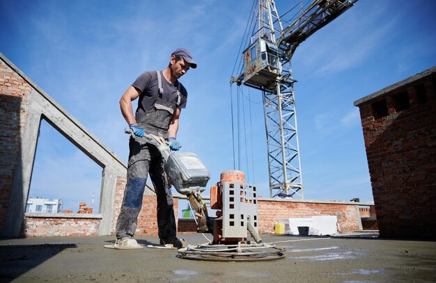 Trabajador nivelando piso fresco con máquina especial