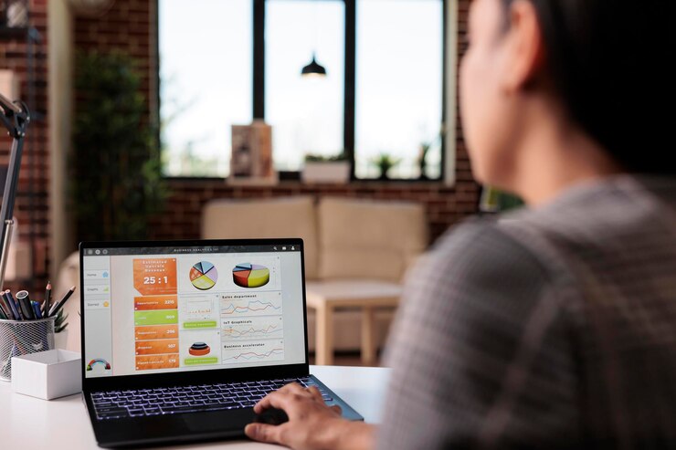 Foto gratuito trabajador de oficina analizando gráficos comerciales en una computadora portátil, usando papeleo e información de investigación para hacer un informe de datos. trabajando desde casa en análisis de inicio con gráficos web, navegando por internet.