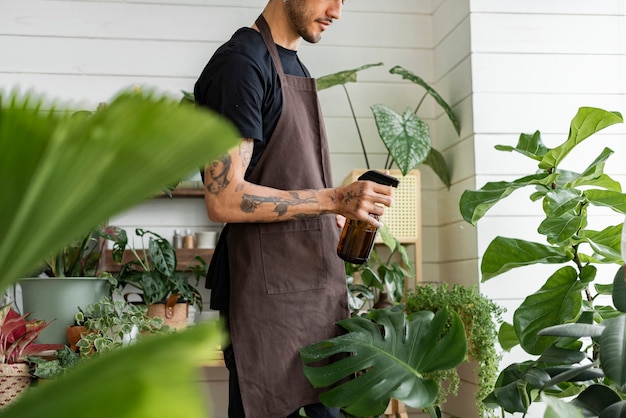 Foto gratuita trabajador de pequeñas empresas nebulizando plantas con un rociador de agua