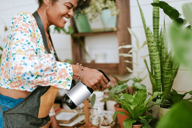 Foto gratuita trabajador de pequeñas empresas nebulizando plantas con un rociador de agua