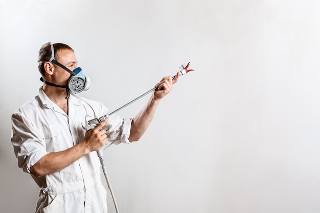 Trabajador pintando la pared con pistola en color blanco.