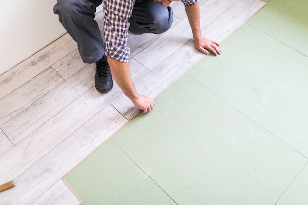 Foto gratuita trabajador procesando un piso con tablas de piso laminado brillante