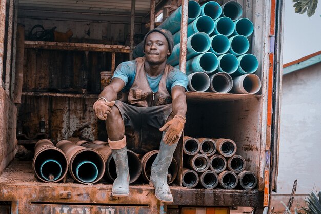 Trabajador sentado sobre tubos oxidados