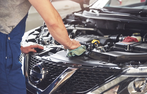 Trabajador de servicio de coche musculoso reparando vehículo.