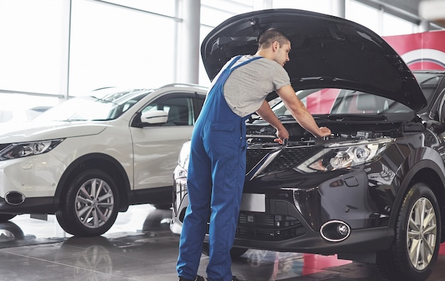 Trabajador de servicio de coche musculoso reparando vehículo.