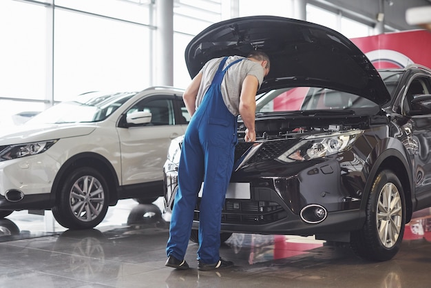 Trabajador de servicio de coche musculoso reparando vehículo.