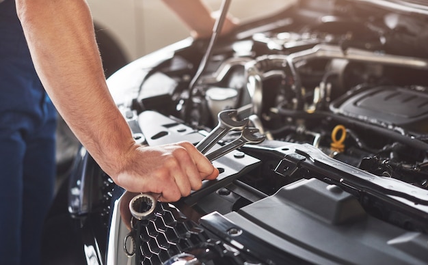 Trabajador de servicio de coche musculoso reparando vehículo.