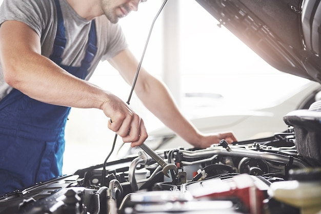 Trabajador de servicio de coche musculoso reparando vehículo.