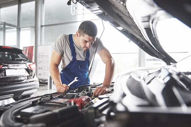 Trabajador de servicio de coche musculoso reparando vehículo.