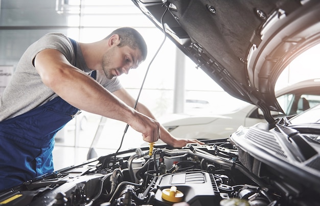 Trabajador de servicio de coche musculoso reparando vehículo.