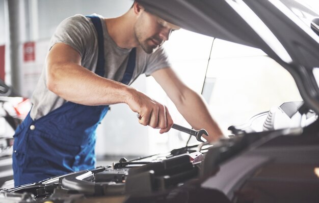 Trabajador de servicio de coche musculoso reparando vehículo.