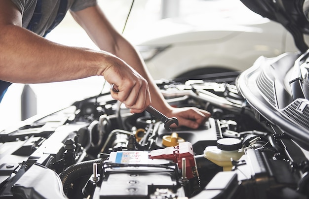 Trabajador de servicio de coche musculoso reparando vehículo.