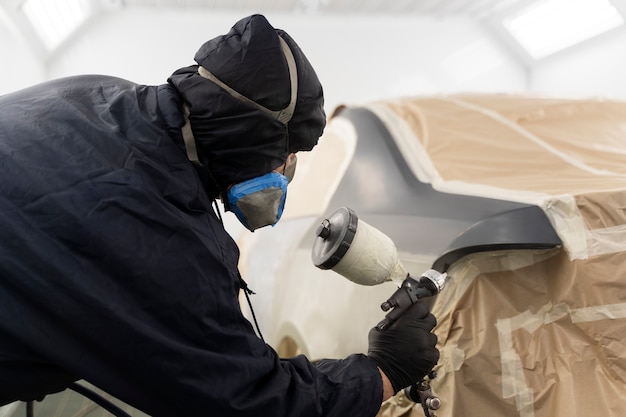 Trabajador de servicio pintando auto en servicio automático