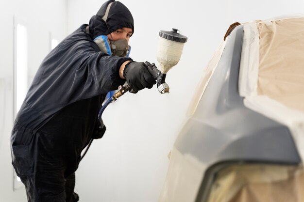 Trabajador de servicio pintando auto en servicio automático