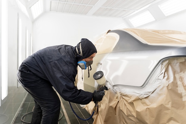 Trabajador de servicio pintando auto en servicio automático