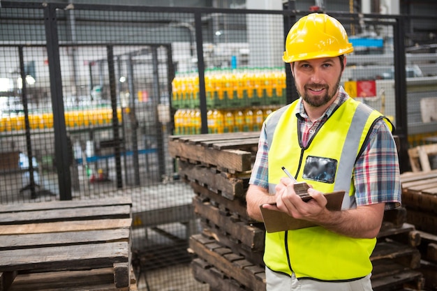 Trabajador de sexo masculino sonriente señalando acerca de los productos en el almacén