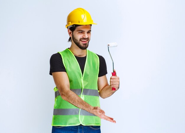 Trabajador sosteniendo un rodillo de acabado blanco para pintar paredes.