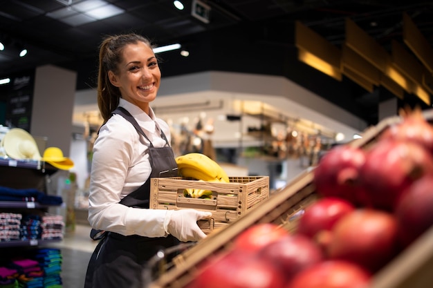 Trabajador de supermercado suministrando alimentos al departamento de frutas