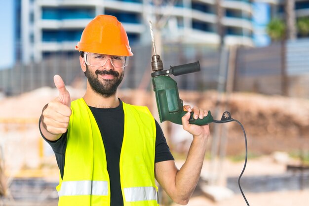 Trabajador con taladro sobre fondo blanco