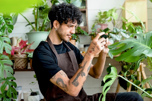 Trabajador de tienda de plantas toma una foto de plantas en macetas