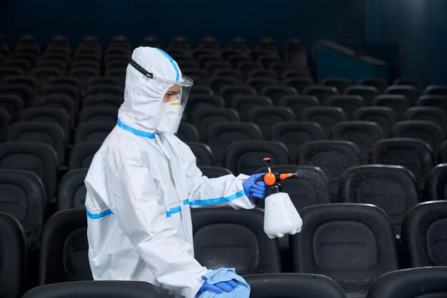 Trabajador en traje especial limpieza de sala de cine con trapo