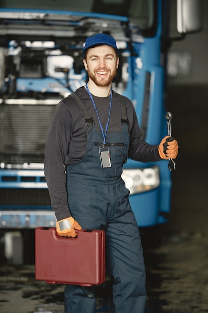 Foto gratuita trabajador en uniforme. el hombre repara un camión. hombre con herramientas