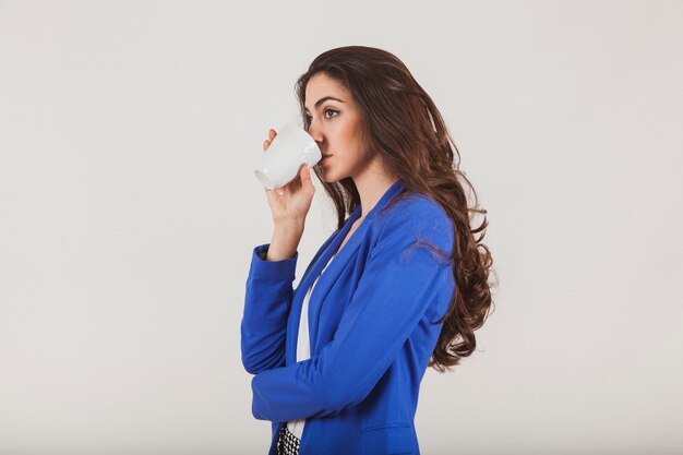 Trabajadora con chaqueta azul bebiendo un café