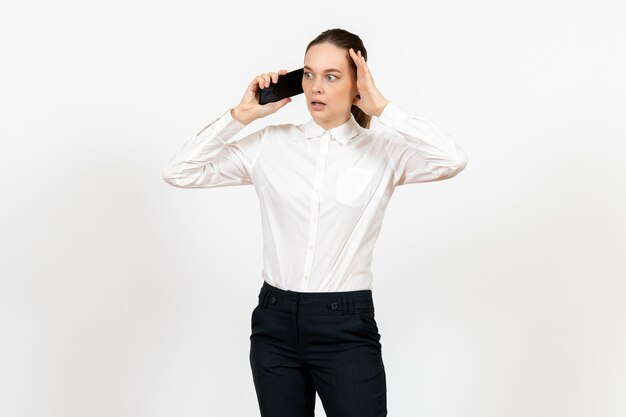 Trabajadora en elegante blusa blanca hablando por teléfono en blanco claro