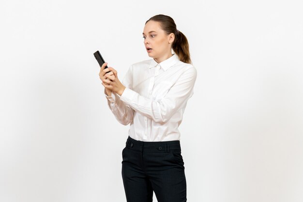 Trabajadora en elegante blusa blanca hablando por teléfono en blanco