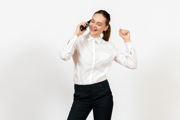 Foto gratuita trabajadora en elegante blusa blanca hablando por teléfono en blanco