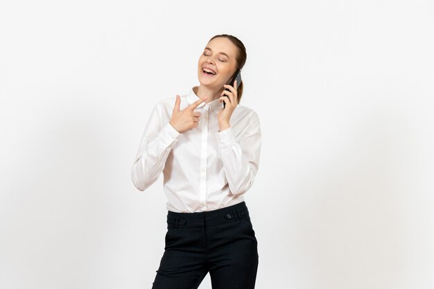 Trabajadora en elegante blusa blanca hablando por teléfono y riendo en blanco