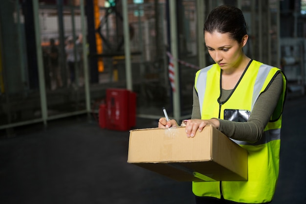 Trabajadora escribiendo en caja en almacén