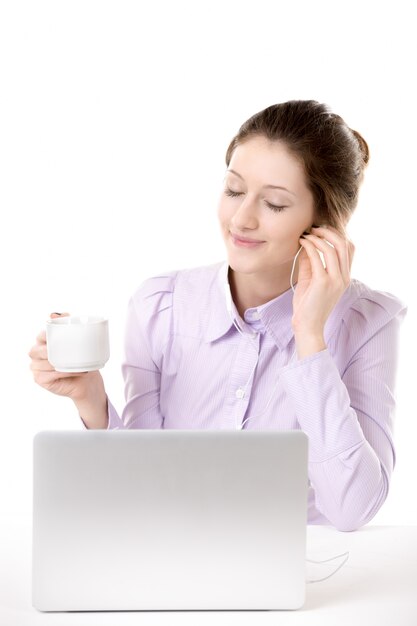 Trabajadora escuchando música mientras sujeta una taza de café