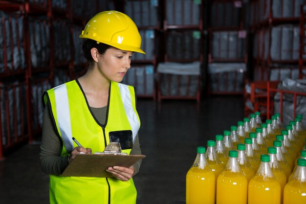 Trabajadora examinando botellas de jugo en la fábrica.