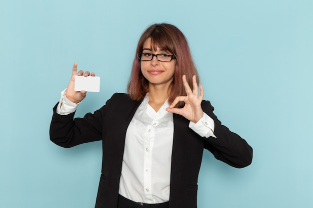 Trabajadora de oficina de vista frontal en traje estricto con tarjeta blanca sobre superficie azul claro