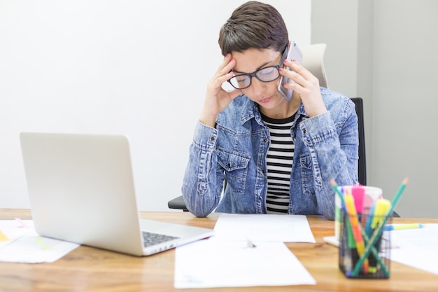 Trabajadora pensativa hablando por teléfono