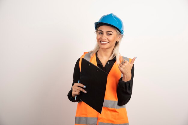 Trabajadora con portapapeles haciendo pulgares sobre fondo blanco. Foto de alta calidad