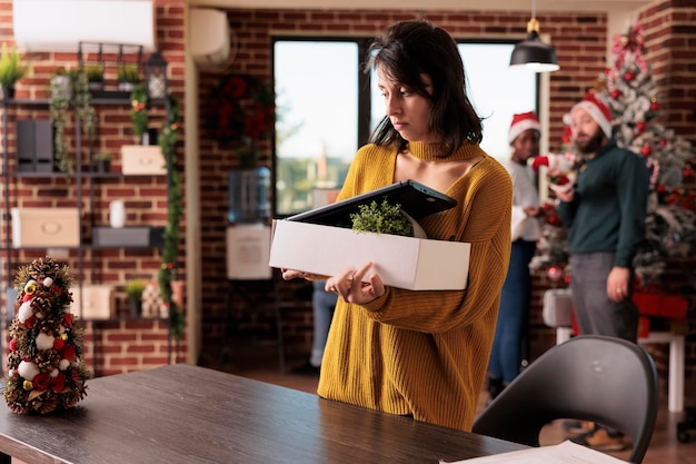 Foto gratuita trabajadora que es despedida del trabajo en navidad, está desempleada y deprimida durante la temporada de vacaciones de invierno. estar descontento por el fracaso profesional y la pérdida del trabajo, despedido de su cargo.