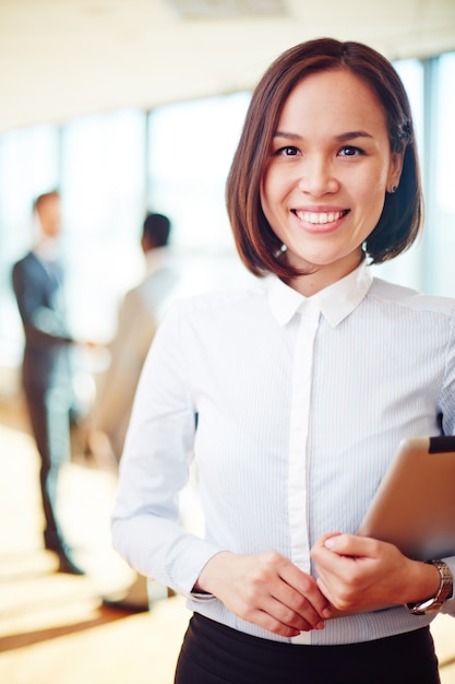 Trabajadora sonriente sosteniendo un sujetapapeles