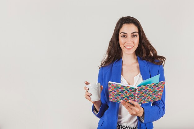 Trabajadora sonriente con taza de café y cuaderno