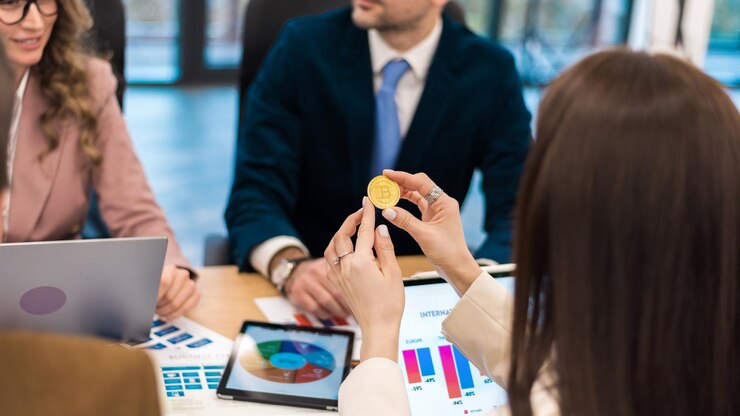 Foto gratuito trabajadora sosteniendo una moneda de criptomoneda física en una oficina