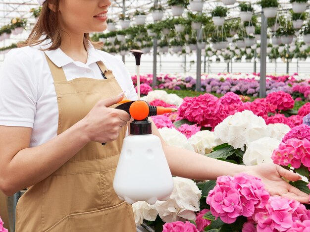 Trabajadora sosteniendo polivizador y regando flores