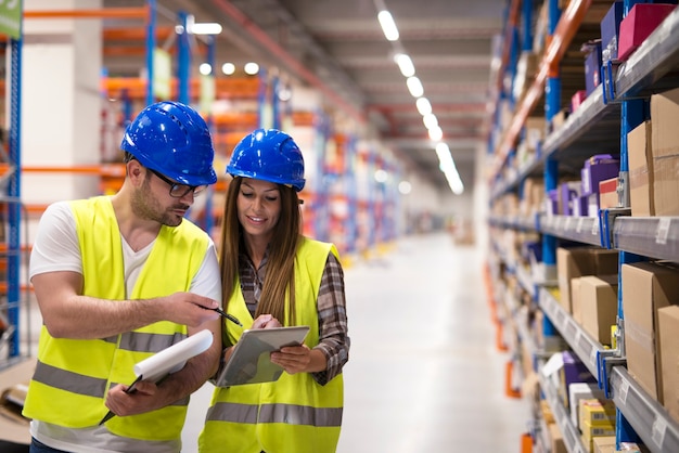 Trabajadores del almacén que controlan el inventario y se consultan entre sí sobre la organización y distribución de mercancías.