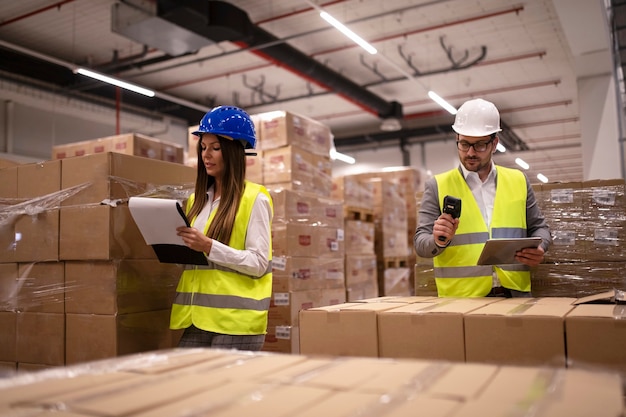 Trabajadores del almacén que utilizan un escáner de código de barras y una tableta y controlan el inventario de mercancías