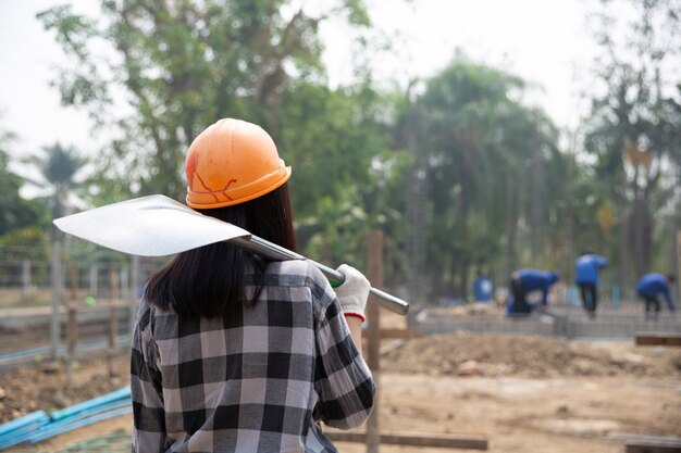 Trabajadores de la construcción llevando una pala al sitio de construcción