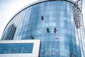 Foto gratuita trabajadores lavando ventanas en el edificio de oficinas