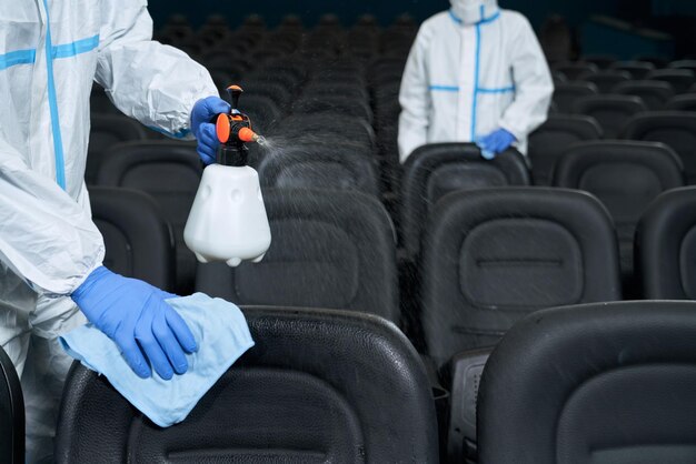 Trabajadores limpiando sillas con desinfectantes en cine