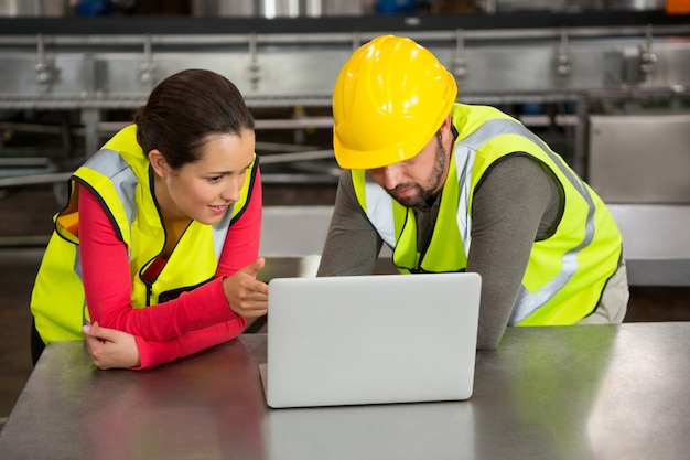 Trabajadores manuales con laptop en la fábrica.